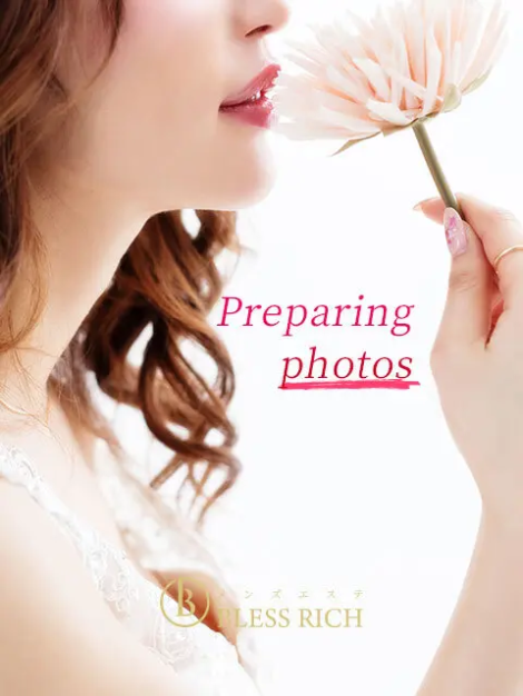 Close-up of a woman holding a pale pink flower near her lips with 'Preparing photos' overlayed in pink text.